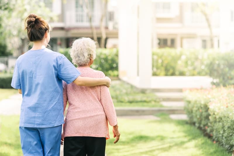 Une aide-soignante qui accompagne une personne âgée.